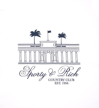 Line drawing of a building with palm trees and Sporty & Rich Country Club Est. 1994 text, features on the Villa T-Shirt - White/Navy. Made in the USA from 100% cotton.
